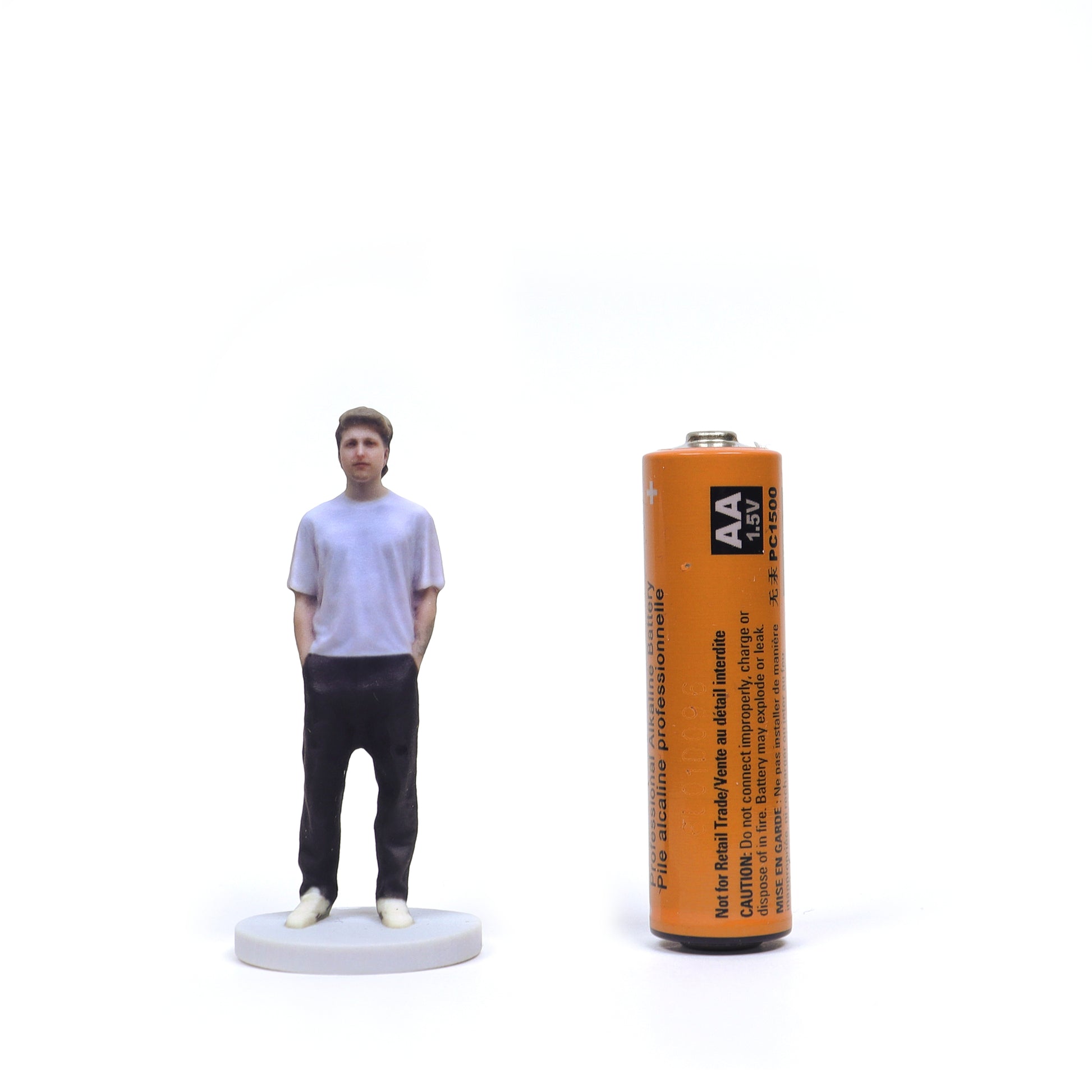 Person Figurine Next To AA Battery Small