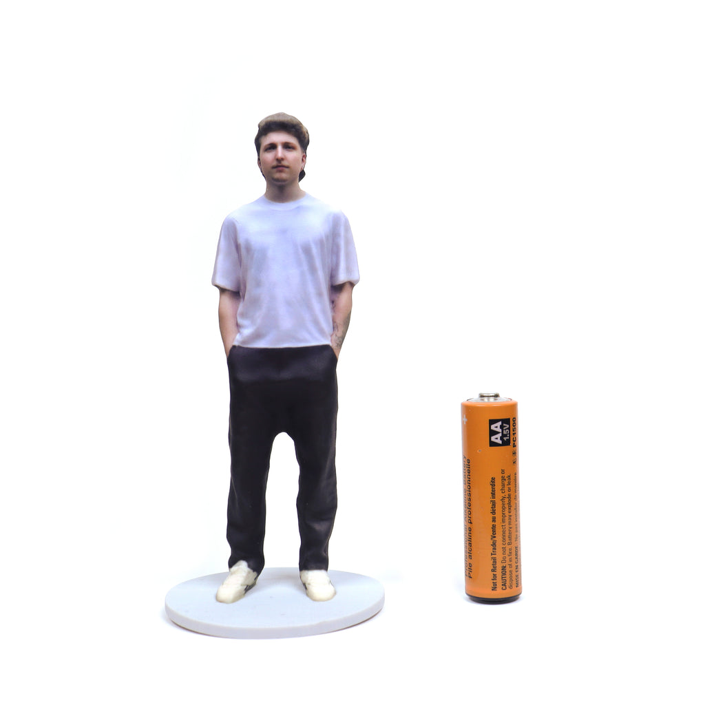 Person Figurine Next To AA Battery Large